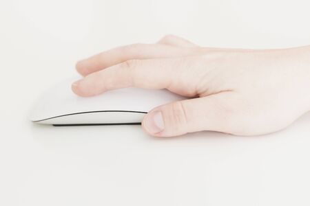 Caucasian female hand, using a white wireless computer mouse, with a nice design, on a white background. Business woman, selective focus, conceptsの写真素材