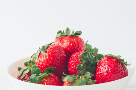 Close up, appetizing and colorful fresh strawberries in a white bowl, ready to eat. Selective focus, copy spaceの写真素材