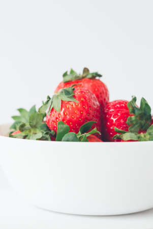 Close up, appetizing and colorful fresh strawberries in a white bowl, ready to eat. Selective focus, copy spaceの写真素材