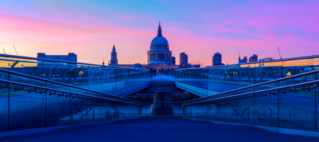 Panoramic view of purple sunset at St Paul's Cathedral and the Millennium Bridge in London with people walking in blurred motionの写真素材