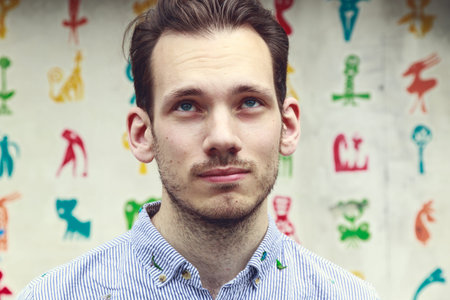 Portrait of a doubtful young man in front of a colourful funky background