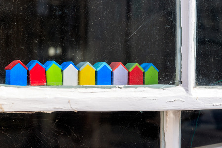 Row of little colourful beach hut wooden ornaments sitting on window frameの写真素材