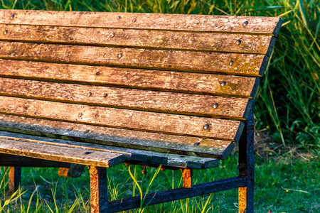 Wooden bench in park with bright yellow sunset light for concept useの写真素材