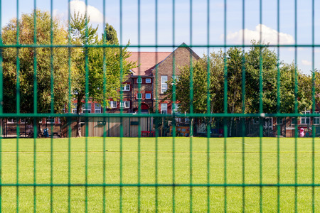 Green fence with house in the background for concept useの写真素材