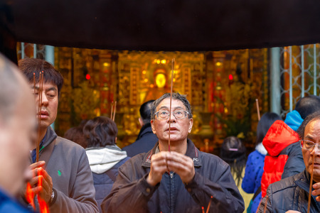 Taipei, Taiwan - January 21, 2017 - A man praying with burning incense, seen through a censer at Lungshan Temple of Mankaのeditorial素材