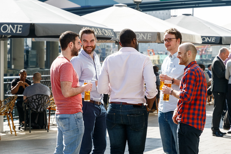 London, UK - May 10, 2017 - Group of young men drinking at a dockside bar in Canary Wharfのeditorial素材