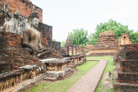 sitting Buddha sculpture among the ruins in Sukhothai historical park, Thailandの写真素材