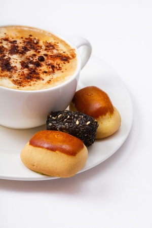 A cup of coffee and sweets on a plate closeup, isolated on a white background の写真素材