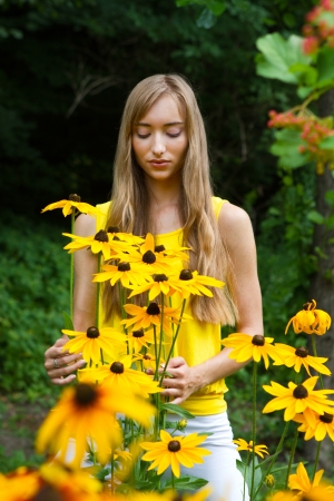 Close-up portrait of a young woman with flowers against a background of treesの写真素材