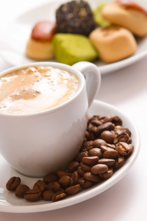 Closeup cup of coffee and sweets on the saucer isolated on a white backgroundの写真素材