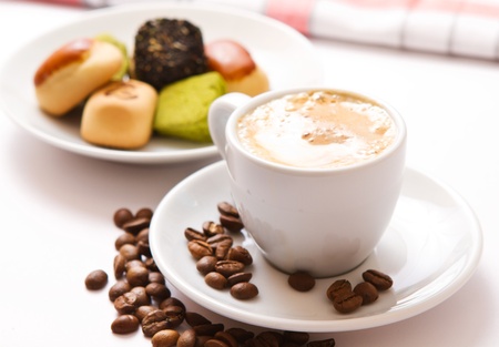 Closeup cup of coffee and sweets on the saucer on the white の写真素材