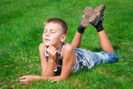 happy boy lying on the grass outdoorsの写真素材
