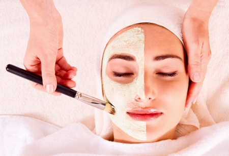 Woman receiving facial mask at beauty salonの写真素材