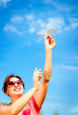 woman starts paper plane in blue sky の写真素材