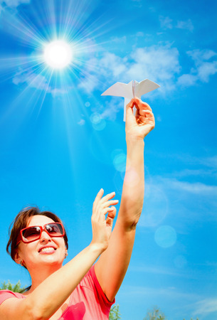 woman hand starts paper plane in blue sky. concept of  dreamの写真素材