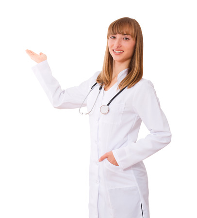 Happy smiling young beautiful female doctor showing blank area for sign or copyspace, isolatedの写真素材