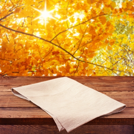 Empty wooden deck table with tablecloth for product montage. Autumn landscape. Free space for your textの写真素材
