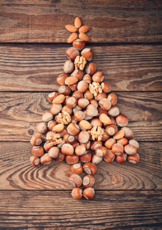 Hazelnuts, filbert on old wooden background. Christmas tree made of hazelnuts on a wooden surfaceの写真素材