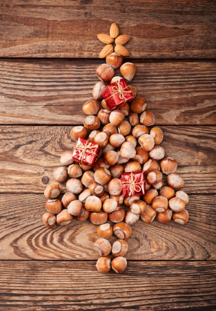 Hazelnuts, filbert on old wooden background. Christmas tree made of hazelnuts on a wooden surfaceの写真素材