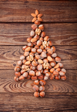 Hazelnuts, filbert on old wooden background. Christmas tree made of hazelnuts on a wooden surfaceの写真素材