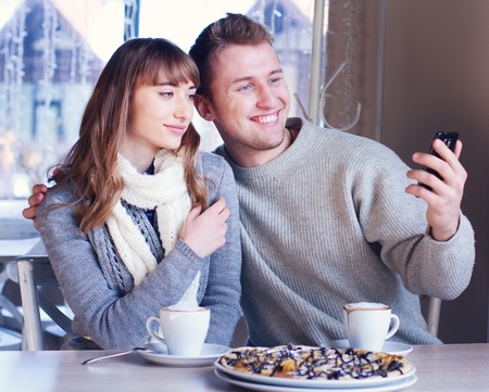 Portrait of Beautiful Young Couple in Love, couple having fun talking in cafe and drink coffee. Concept of relationship, love story, preparations for wedding, fashionable clothingの写真素材