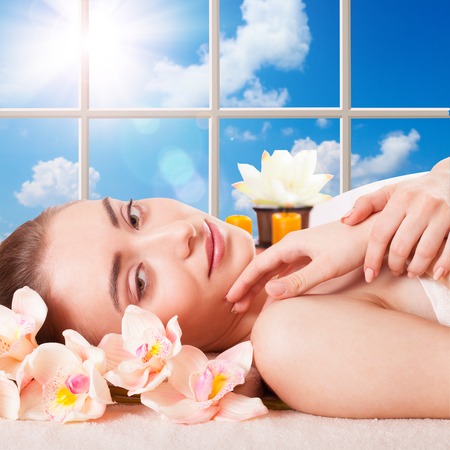 Beautiful Young Woman Getting Massage Facial and Body in Spa Salon  Treatment Cosmetics Beauty Care Body Herbs Surrounded by Flowersの写真素材