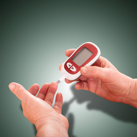 Woman makes measurement Testing  high blood sugar  Diabetes concept glucometer for glucose level blood test in hand and healthy organic food on white backgroundの写真素材