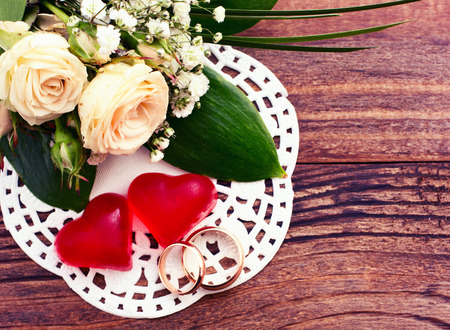 Bridal bouquet of white flowers on wooden surface. Wedding flowers of delicate roses wedding rings. Wedding bouquet background. Empty wooden tabletopの写真素材