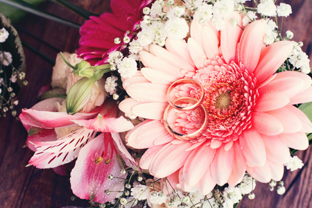 Bridal bouquet of white flowers on wooden surface. Wedding flowers of delicate roses wedding rings. Wedding bouquet background. Empty wooden tabletopの写真素材