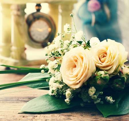 Bridal bouquet of white flowers on wooden surface. Wedding flowers of delicate roses wedding rings. Wedding bouquet background. Empty wooden tabletopの写真素材