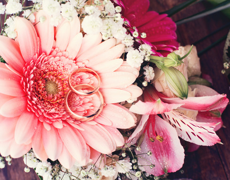 Bridal bouquet of white flowers on wooden surface. Wedding flowers of delicate roses wedding rings. Wedding bouquet background. Empty wooden tabletopの写真素材