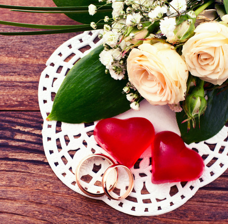 Bridal bouquet of white flowers on wooden surface. Wedding flowers of delicate roses wedding rings. Wedding bouquet background. Empty wooden tabletopの写真素材