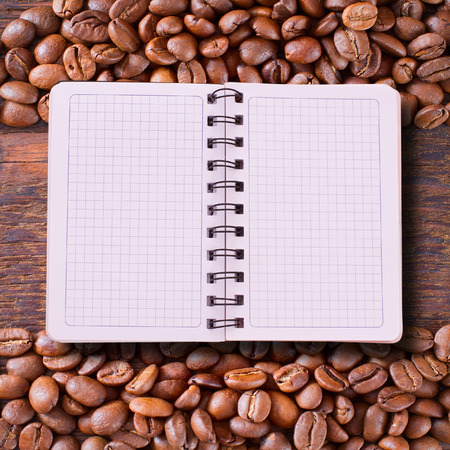 Pure notebook for menu, recipe record on wooden table top view. Coffee beans as background for product pages of recipes and menus cookbooksの写真素材