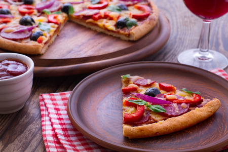 Pizza with ham peppers and olives with delicious fresh food on a wooden table. Ingredients tomatoes, salami and spices for pizza.の写真素材
