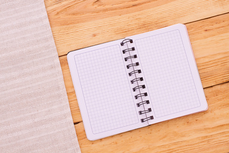 Pure notebook for recording menu, recipe on red checkered tablecloth tartan. Wooden table close up view from topの写真素材