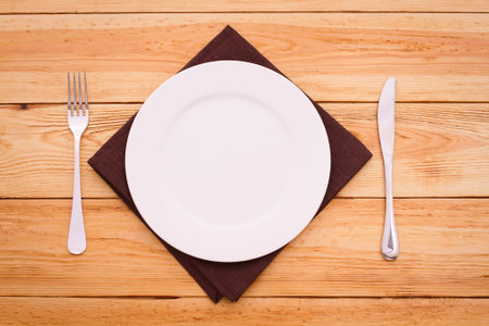Cutlery on red checkered tablecloth tartan on a wooden table top view. The product page for recipes...