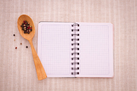 Pure notebook for recording menu, recipe on red checkered tablecloth tartan. Wooden table close up view from topの写真素材