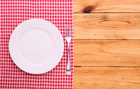 Cutlery on red checkered tablecloth tartan on a wooden table top view. The product page for recipes and menus cookbooksの写真素材