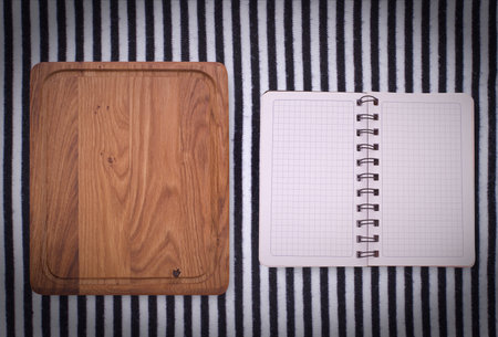 Pure notebook for recording menu, recipe on red checkered tablecloth tartan. Wooden table close up view from topの写真素材