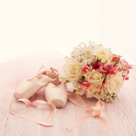 Ballet shoes. Pointe shoes on wooden background. Beautiful bouquet of white rosesの写真素材