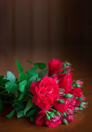 Beautiful bouquet of flowers on wooden table old. Vintage red roses in retro style.の写真素材