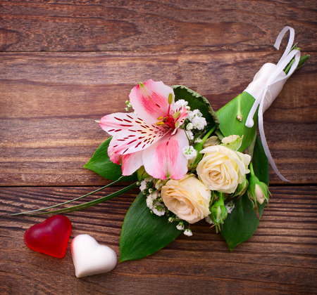 Flowering branch with white delicate flowers on wooden surface. Wedding rings, wedding bouquet background.の写真素材