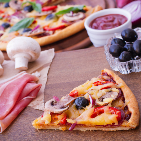 Pizza with ham, pepper and olives. Delicious fresh pizza served on wooden table.の写真素材