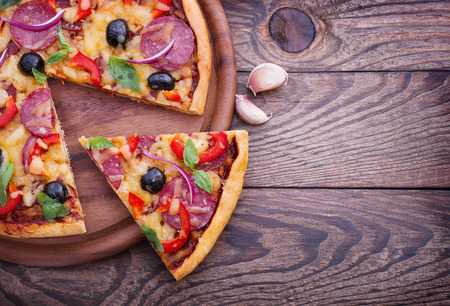 Pizza with ham, pepper and olives. Delicious fresh pizza served on wooden table.の写真素材