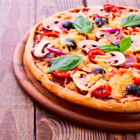 Pizza with ham, pepper and olives. Delicious fresh pizza served on wooden table.の写真素材