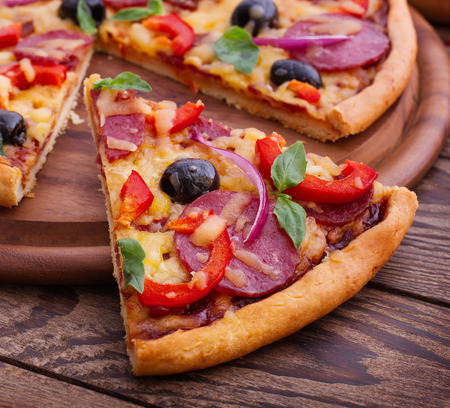 Pizza with ham, pepper and olives. Delicious fresh pizza served on wooden table.の写真素材