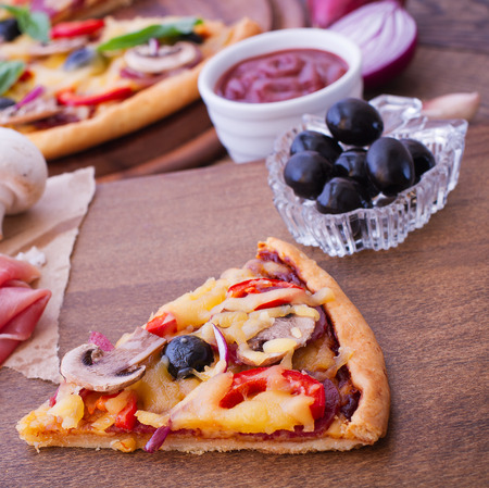 Pizza with ham, pepper and olives. Delicious fresh pizza served on wooden table.の写真素材