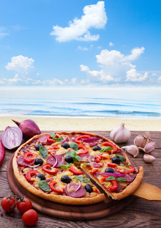Pizza with ham, pepper and olives. Delicious fresh pizza served on wooden table.の写真素材
