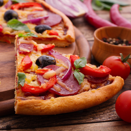 Pizza with ham, pepper and olives. Delicious fresh pizza served on wooden table.の写真素材