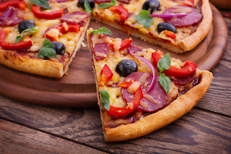 Pizza with ham, pepper and olives. Delicious fresh pizza served on wooden table.の写真素材